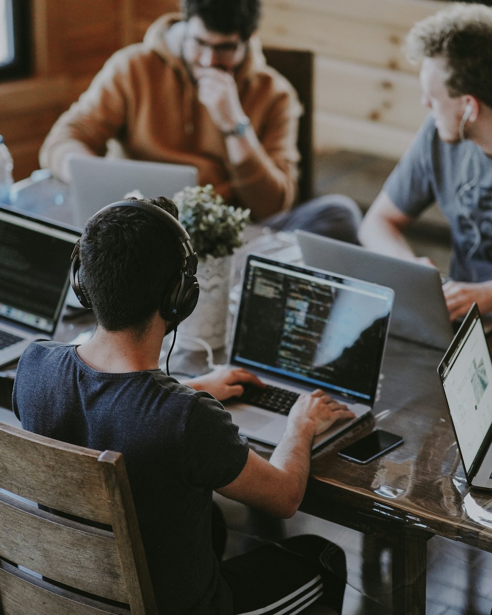 Team bei der gemeinsamen Planung an Laptops rund um einen Tisch